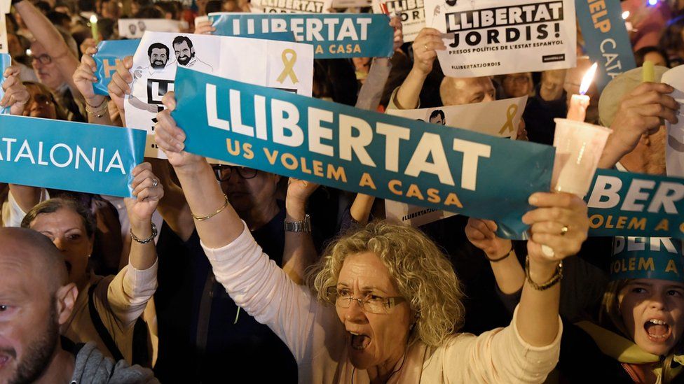 People hold placards reading "Freedom" during candle-lit demonstration in Barcelona against the arrest of two Catalan separatist leaders on October 17, 2017.