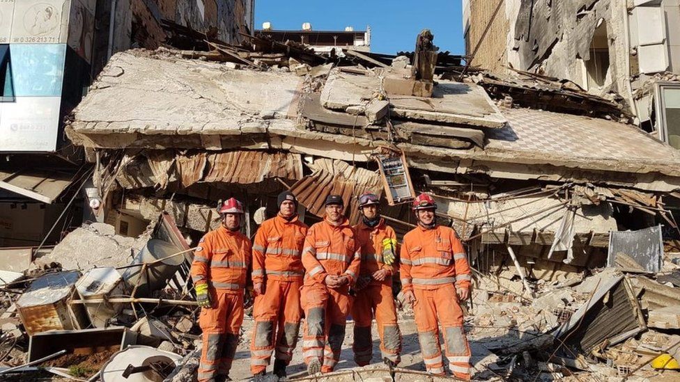 vier Feuerwehrleute auf Trümmern