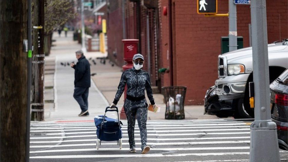 A woman wearing a mask crosses a road in Queens, New York (30/03/20)