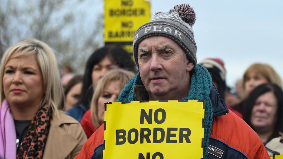 Protestor holding a "no border, no barrier" sign