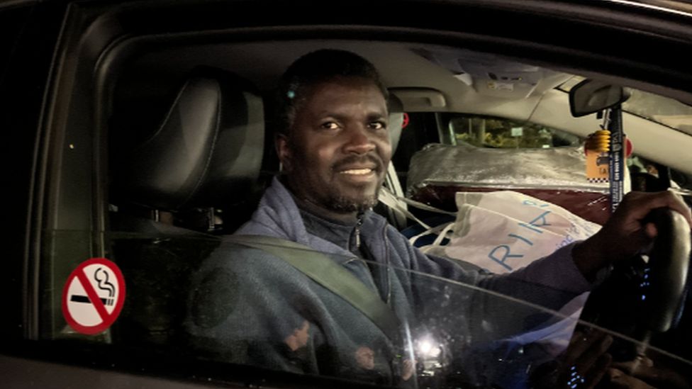 A man sitting in his car looking out through the driver's side window