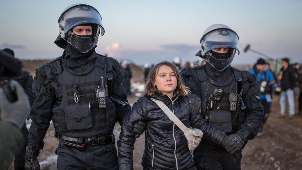 Грета Тунберг в окружении двух полицейских
