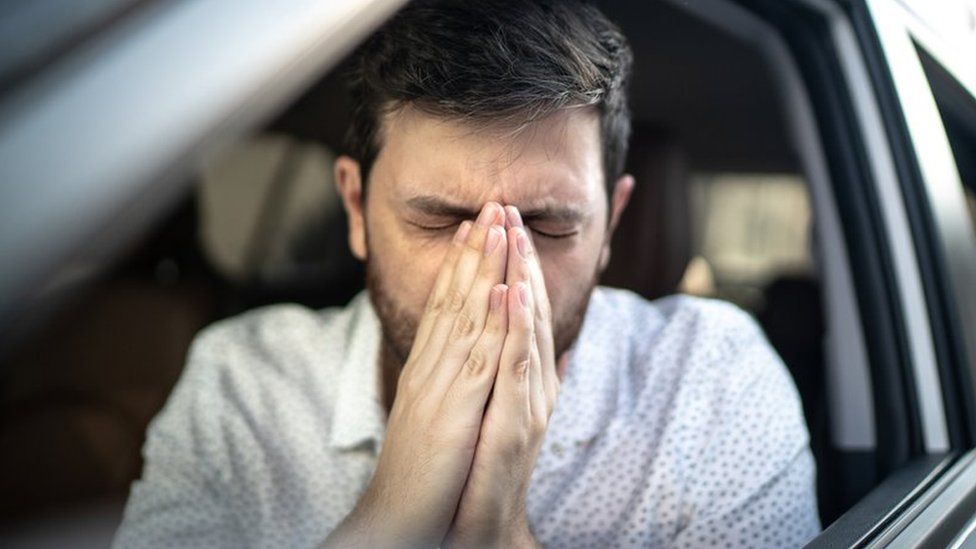 Man holding in a sneeze while in a car