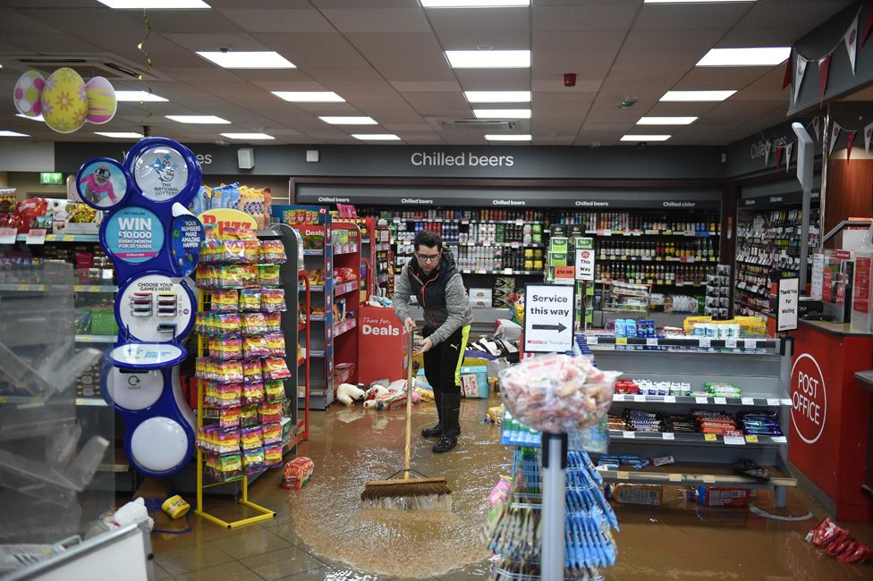 A man sweeps up flood water in a convenience store in Tenbury Wells in western England, after the River Teme broke its banks.