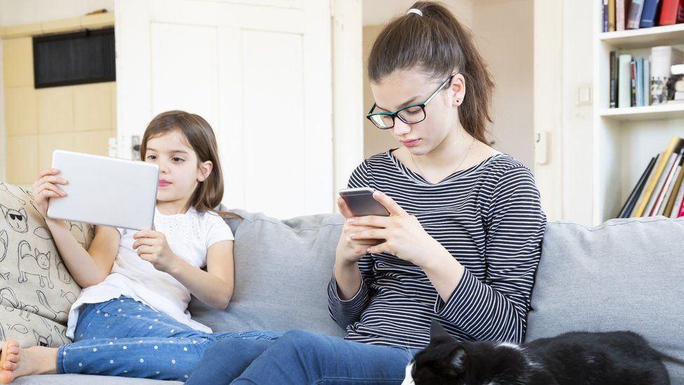 Two children using smartphones and tablets