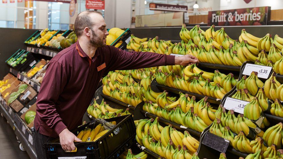Сотрудник Sainsbury's укладывает бананы
