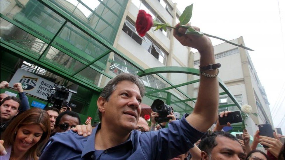 Fernando Haddad waves a red rose after casting his vote