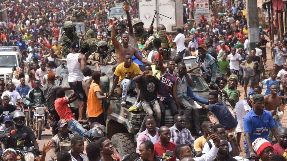 People celebrate in the streets with members of Guinea's armed forces after the arrest of Guinea's president, Alpha Conde, in a coup d'etat in Conakry, September 5, 2021.