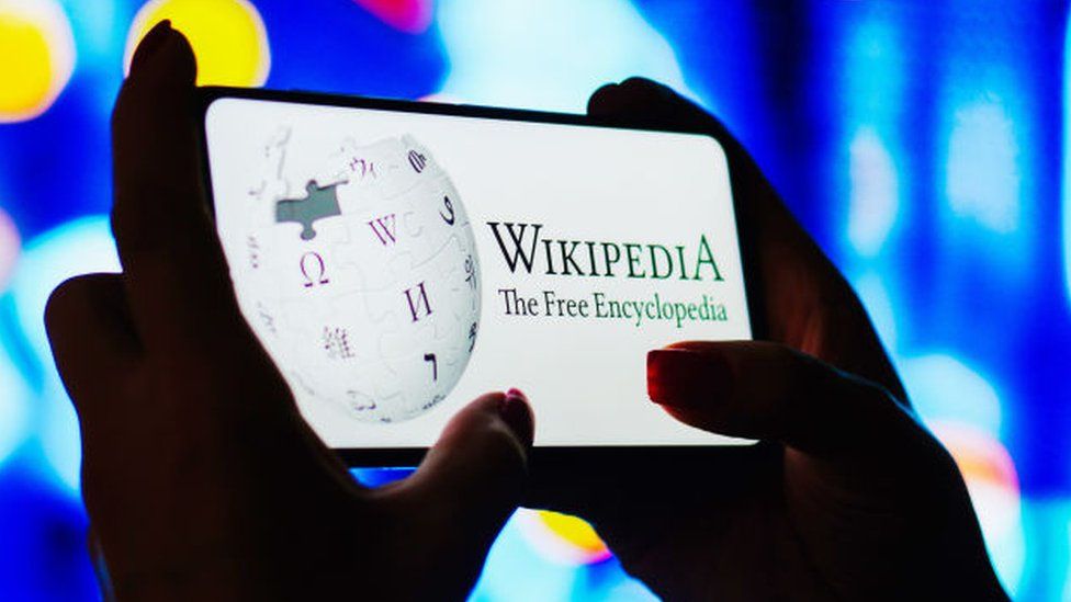 Женщина держит смартфон с Википедией на экране