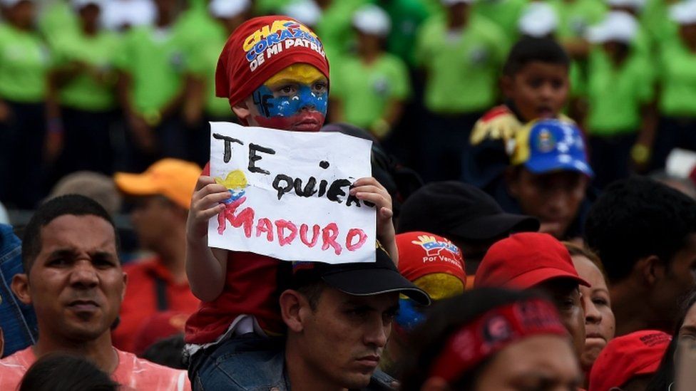 A boy holds a sign reading "I love you Maduro" -referring to Venezuelan President Nicolas Maduro- during rally in Caracas on May 14,
