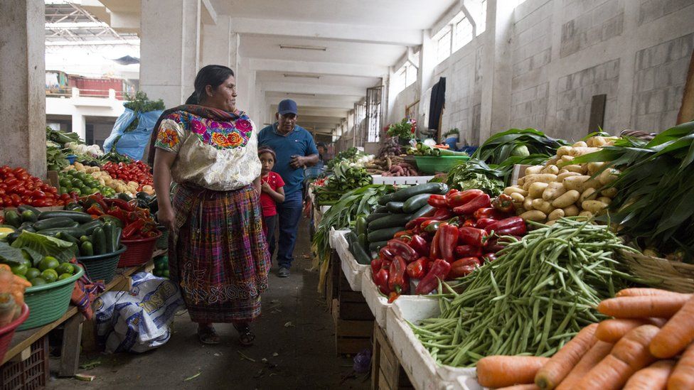 A family shops for vegetables at a market in Zunil