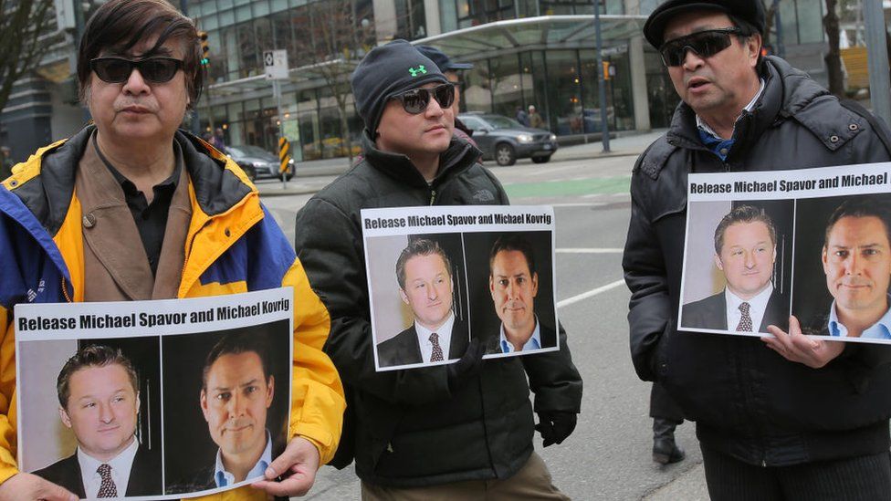 Protesters hold signs calling for the release of Michael Spavor and Michael Kovrig