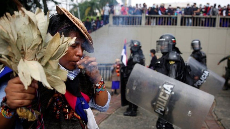 An indigenous person performs a ritual in front of the authorities after protesters knocked down the statue of the founder of the city, Spanish conqueror Sebastian de Belalcazar, during the protests against the tax reform called by the workers" centrals in Cali, Colombia, 28 April 2021