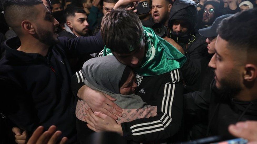 A Palestinian teen hugs a family member after being released