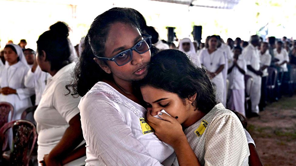 Two women mourn during a funeral service at St Sebastian's Church in Negombo on April 23, 2019