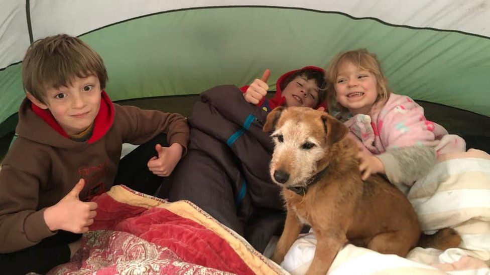 Three children with dog in tent