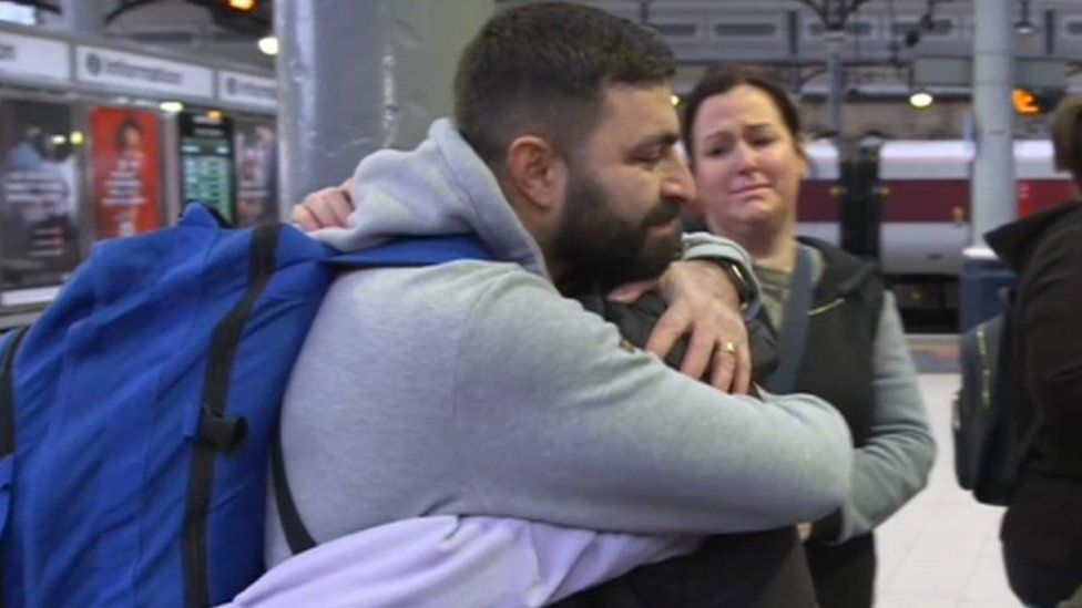 Suleyman hugging family at a train station