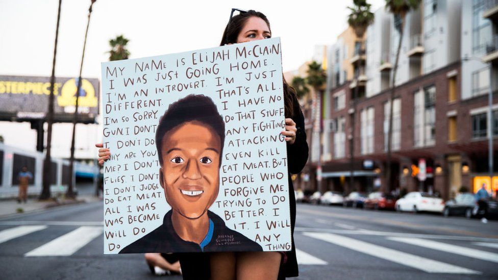 A woman holds a sign at a candlelight vigil for Elijah McClain in California in 2020