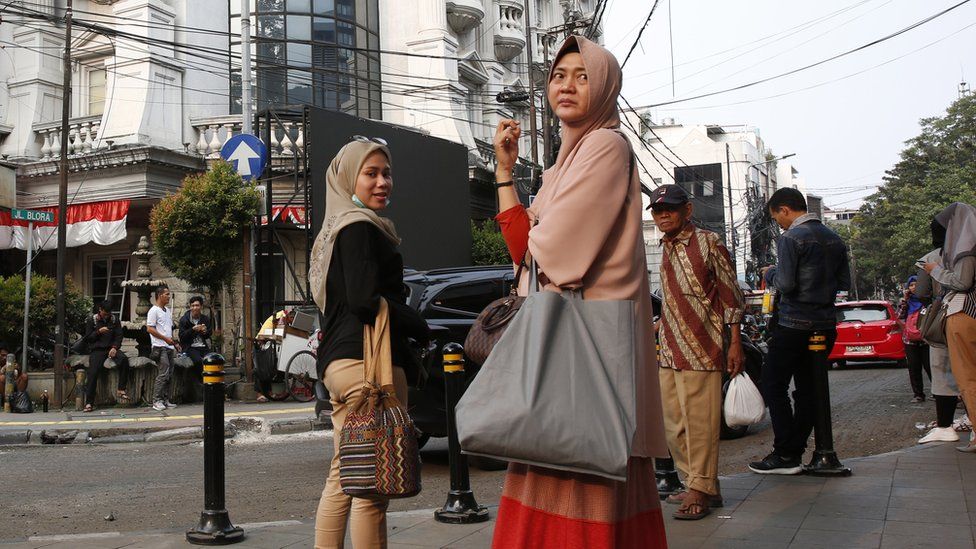 Passengers wait outside a train station in Jakarta