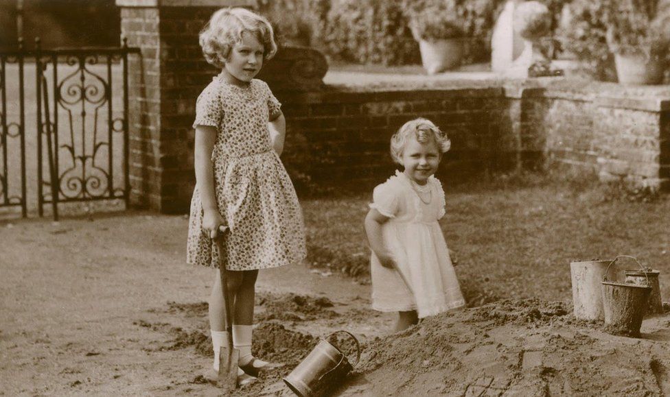 Two young girls play in a sandpit