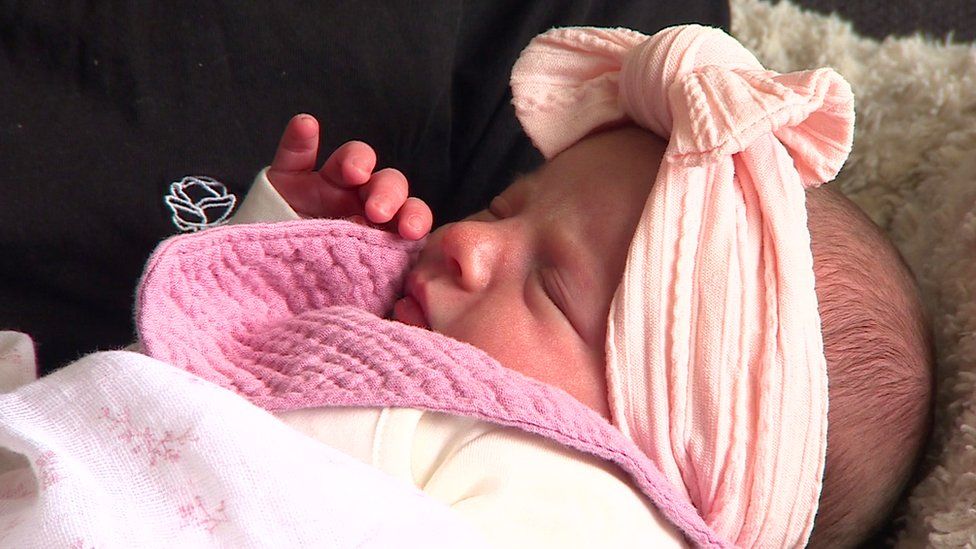A newborn baby in a pink headband