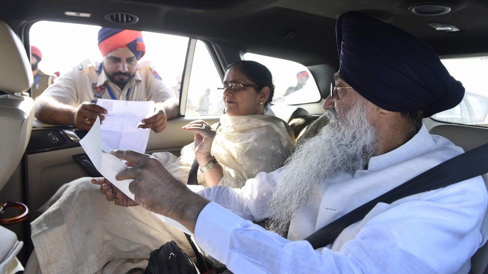 Indian Sikhs show papers to Indian border guards before crossing to Pakistan