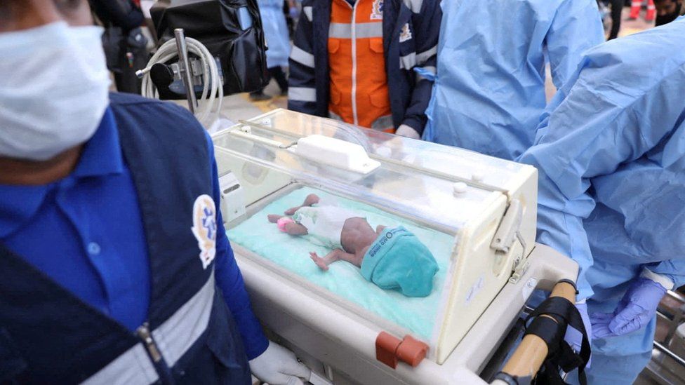 Medics transfer a premature Palestinian baby in an incubator to an ambulance on the Egyptian side of the Rafah border crossing with Gaza (20 November 2023)