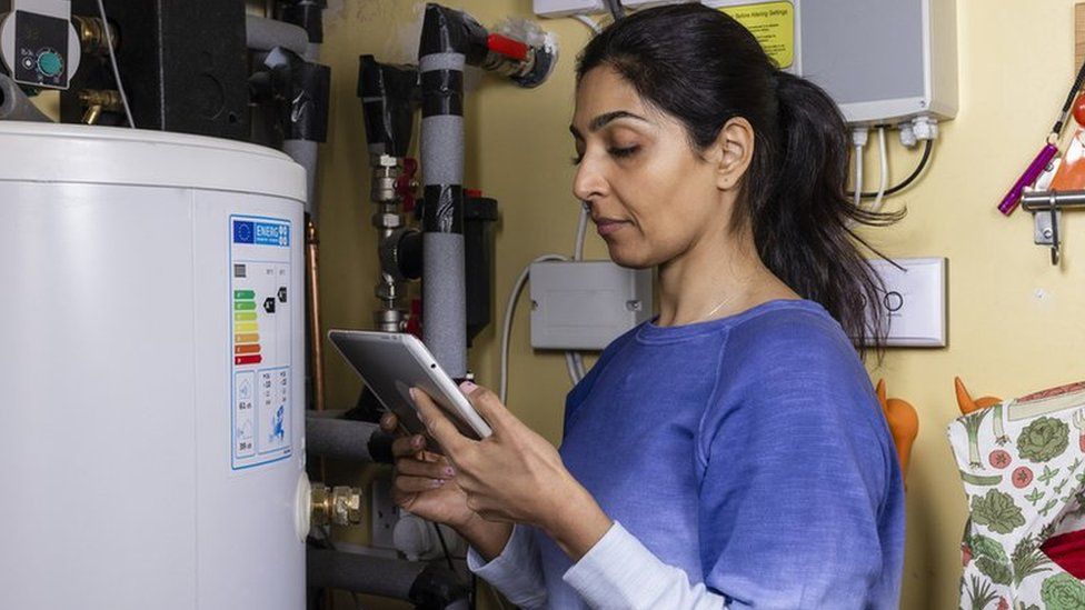 Woman changing thermostat on boiler