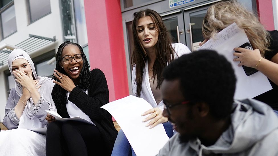 A group of students react with exam results in hands outside an academy in Acton