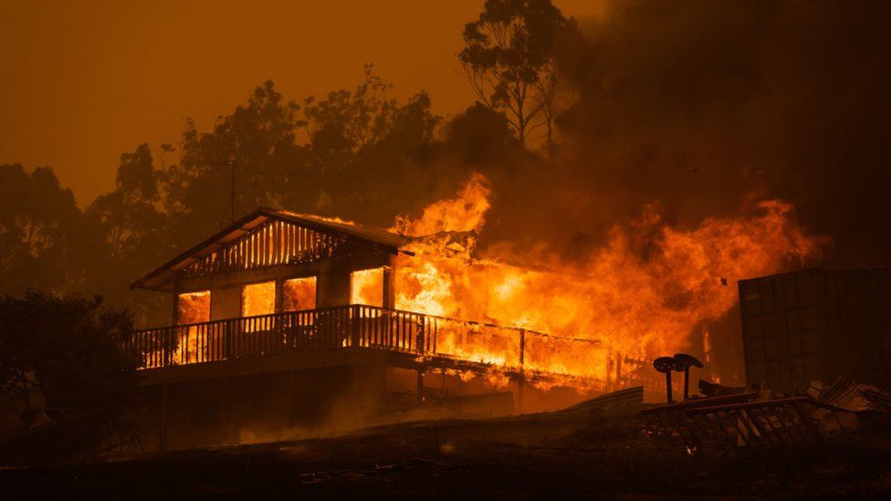 A house is engulfed by bushfire flames