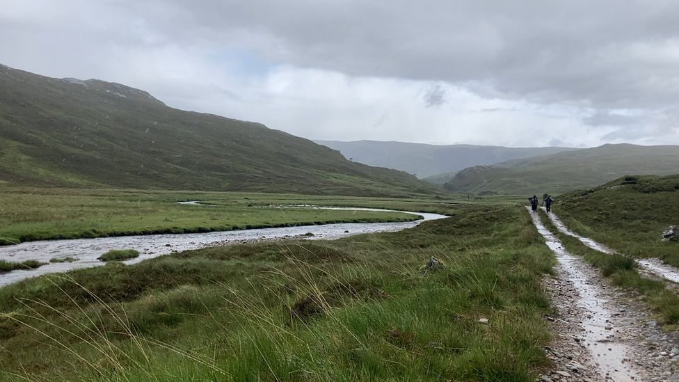 Highland landscape with a stream and people in the distance
