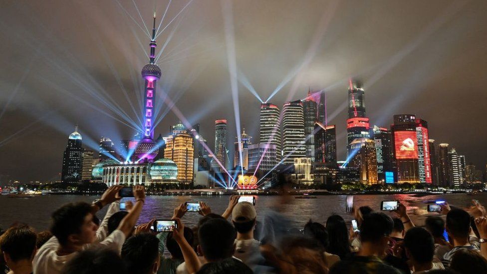 Spectators look at a light show on the Bund promenade in Shanghai