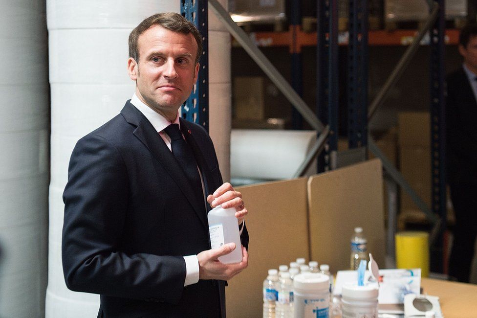 French president Emmanuel Macron with some bottles of hand sanitiser