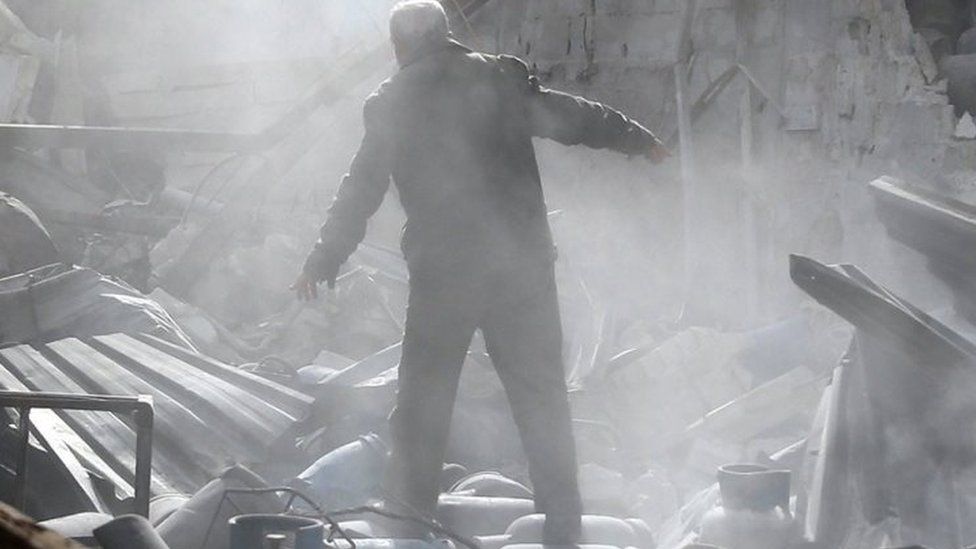 A man stands on the rubble of damaged buildings after an air strike on the rebel-held town of Mesraba in Eastern Ghouta, Syria. Photo: 26 November 2017