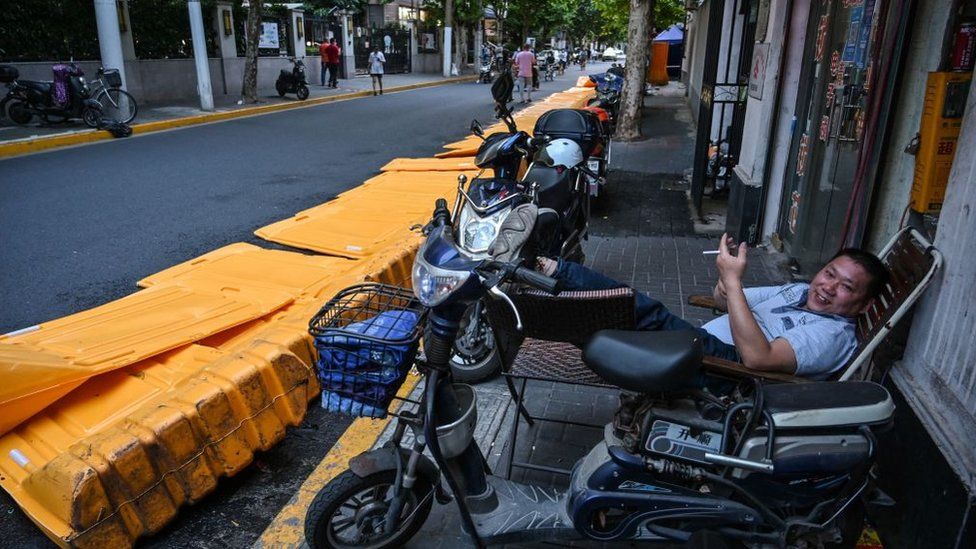 A man rests beside barriers, erected on March 19 according to local residents as part of pandemic lockdowns in the area and taken down earlier this afternoon, in the Jing' an district of Shanghai on May 31, 2022, as the city prepares to lift more curbs after two months of heavy-handed restrictions.