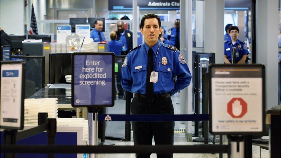 Сотрудник службы безопасности TSA стоит на контрольно-пропускном пункте