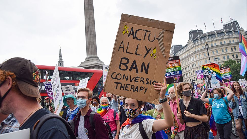 A demonstrator holds a placard that says Actually Ban Conversion Therapy in Trafalgar Square during the Reclaim Pride protest.
