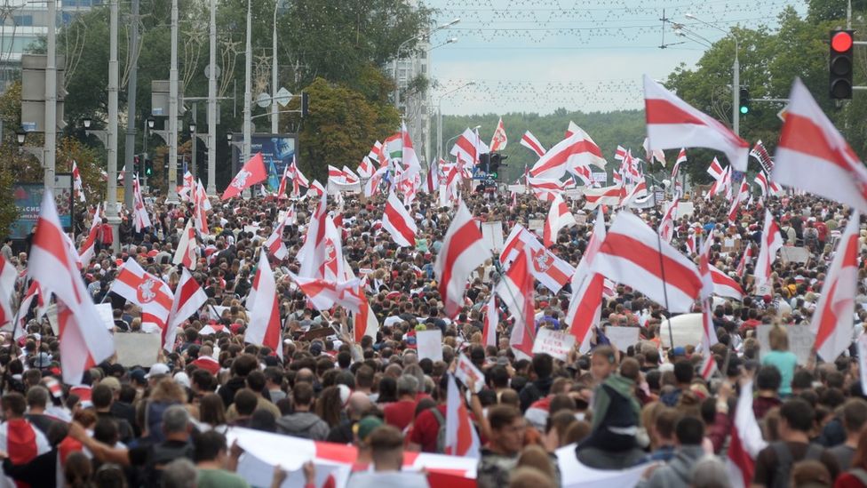 Crowd of pro-democracy protesters waving red and white flags in Belarus