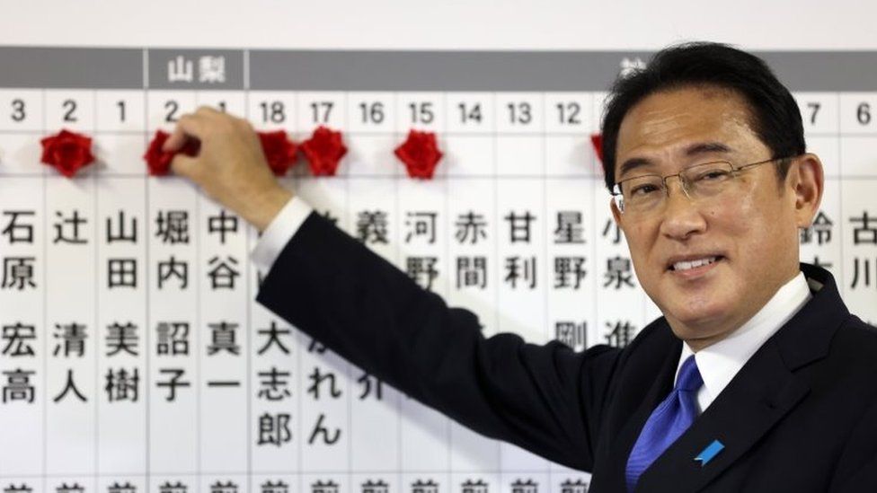 Japanese Prime Minister Fumio Kishida puts rosettes by LDP successful election candidates' names on a board at the party headquarters in Tokyo. Photo: 31 October 2021