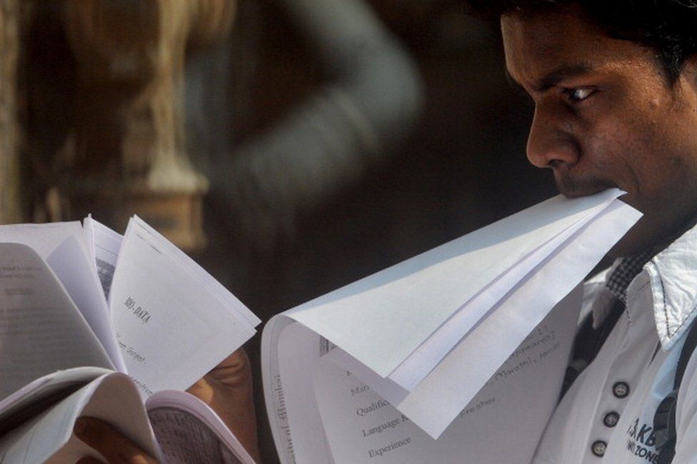 An Indian youth looks through papers as he stands in a queue to apply for a job at a jobs fair in Mumbai on October 12, 2011.