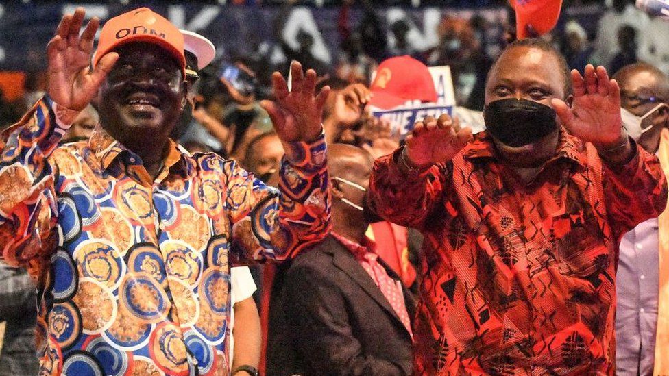 Kenya's President Uhuru Kenyatta (R) flanked by oppostion leader Raila Odinga, wave to deleagates of Orange Democratic Movement