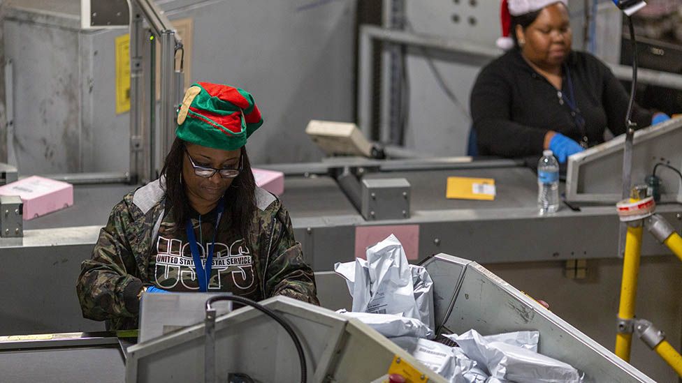 Почтовый работник из США сортирует посылки в праздничные дни