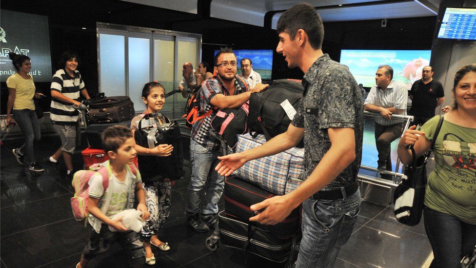 A picture taken on August 13, 2012 shows Armenian man (L) as he meets his relatives upon their arrival from Syria at Zvarnots airport outside Yerevan.