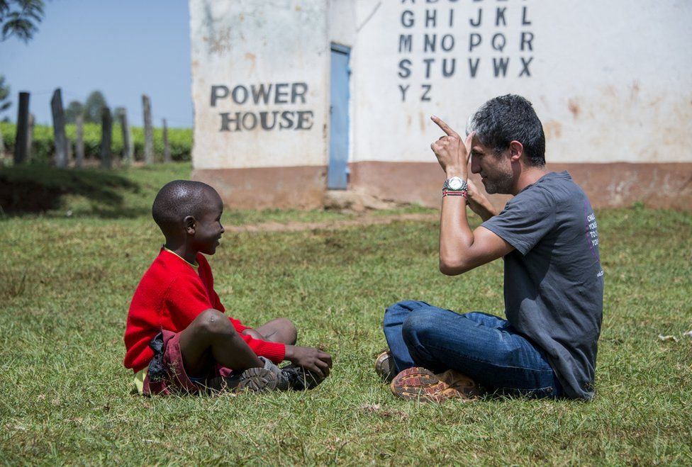 A man teaches a child sign language.