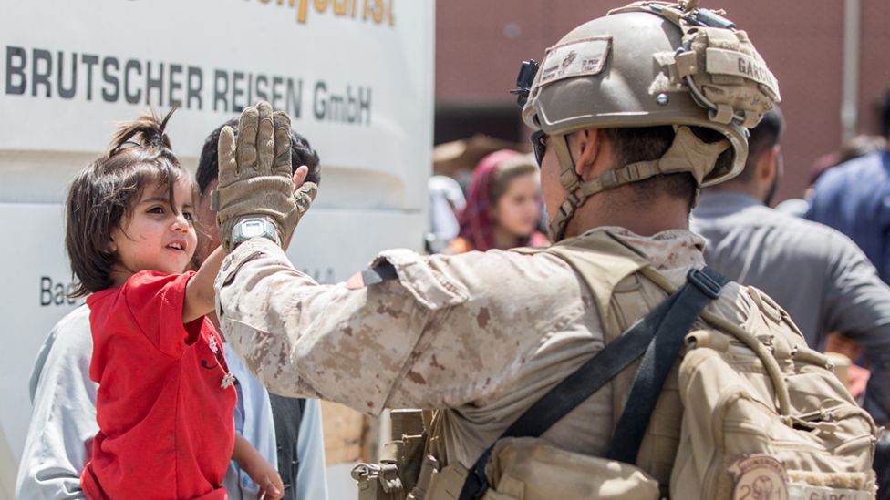 A US Marine receives a high-five from a child during an evacuation at Hamid Karzai International Airport, Kabul, Afghanistan, 21 August 2021