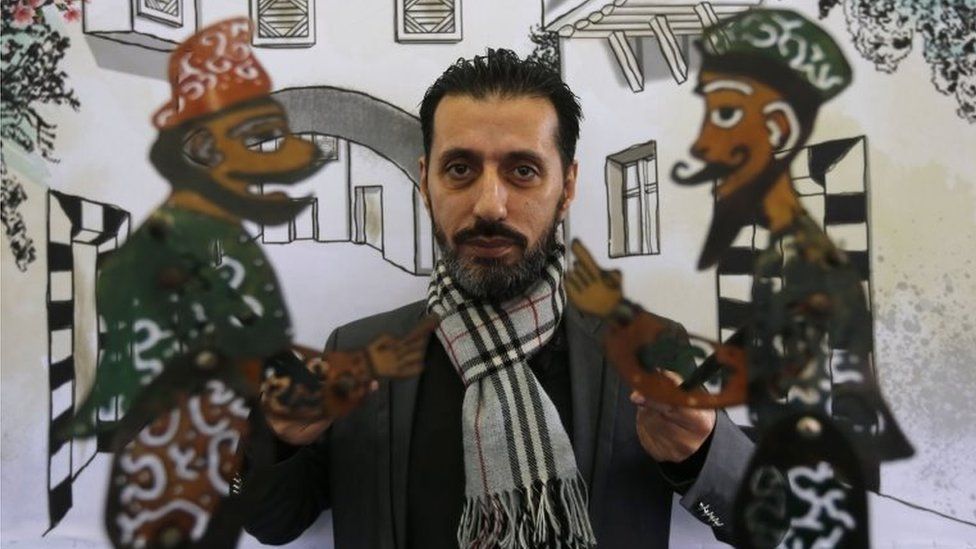 Syrian last shadow puppeteer Shadi al-Hallaq holds his puppets Karakoz (L) and Eiwaz (R) before a presentation in Damascus on 3 December 2018.