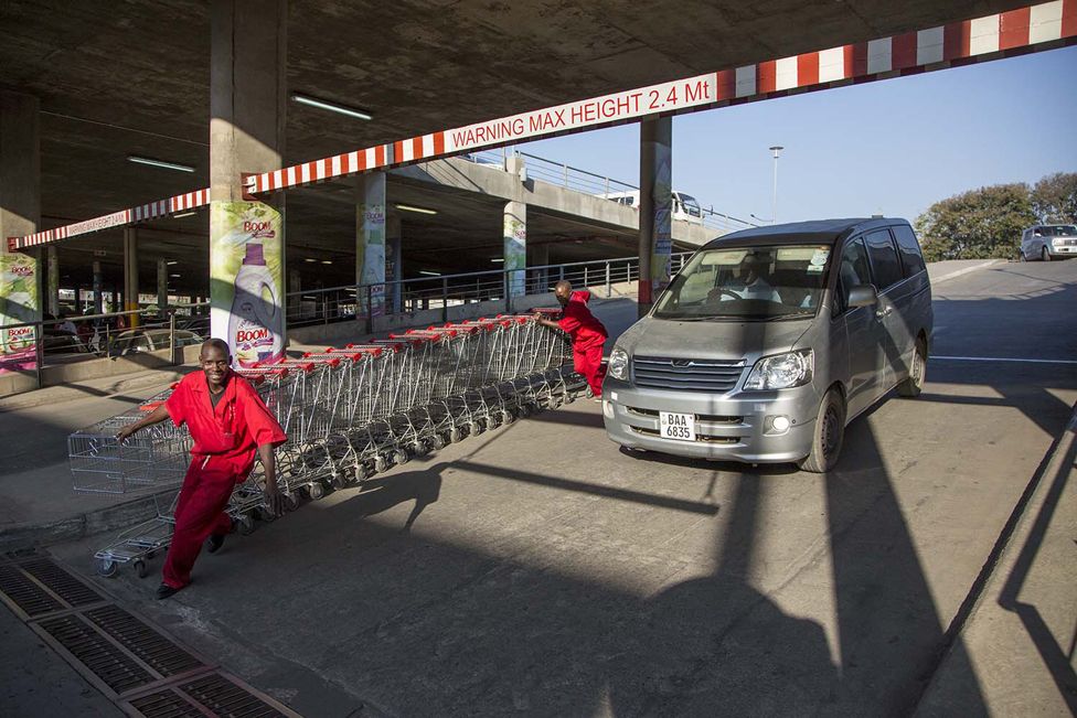 Shopping centre workers return empty trolleys from the car park