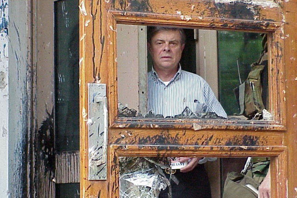 Ambassador James Sasser looks through the broken doors of the a US embassy building in Beijing