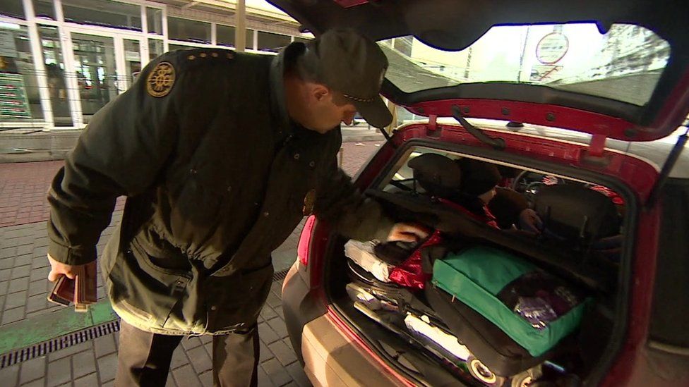 A border guard in Lithuania inspects a car