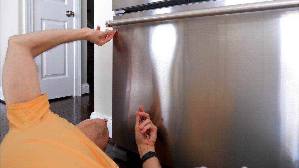 Чоловік ремонтує холодильник